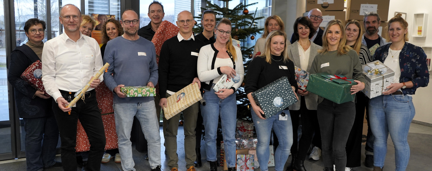 Mitarbeitende der Testo SE & Co KgaA und Testo Industrial Services stehen vor dem Weihnachtsbaum und haben Geschenke in der Hand