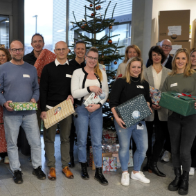 Mitarbeitende der Testo SE & Co KgaA und Testo Industrial Services stehen vor dem Weihnachtsbaum und haben Geschenke in der Hand