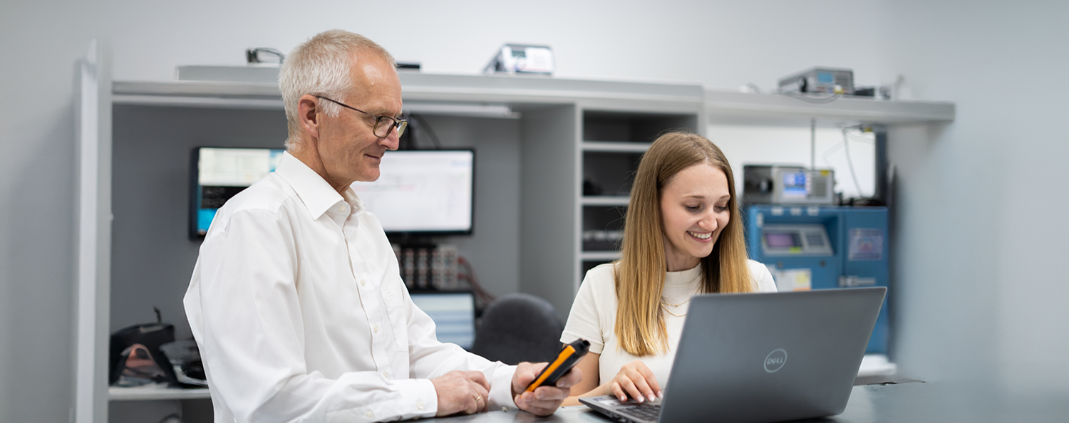 Test equipment management system PRIMAS connect A man and a woman look at a laptop in a laboratory.