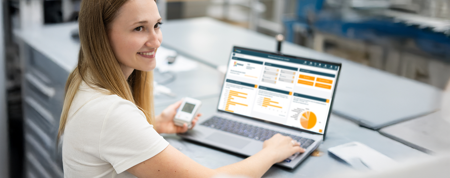 PRIMAS online & mobile A woman is holding a logger in her hand and has a laptop open with PRIMAS online.