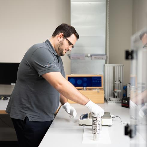 Calibration in the field of force and scales A man calibrates a scale in the mechanical laboratory